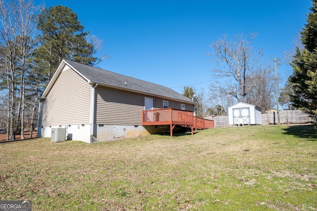 rear view of house with a wooden deck, central air condition unit, a lawn, and a storage unit