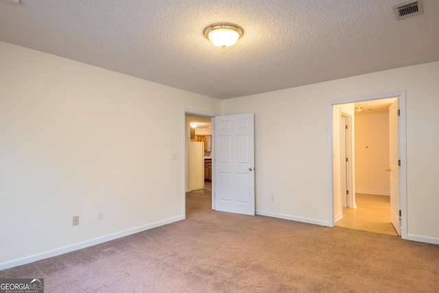 unfurnished bedroom featuring light carpet and a textured ceiling