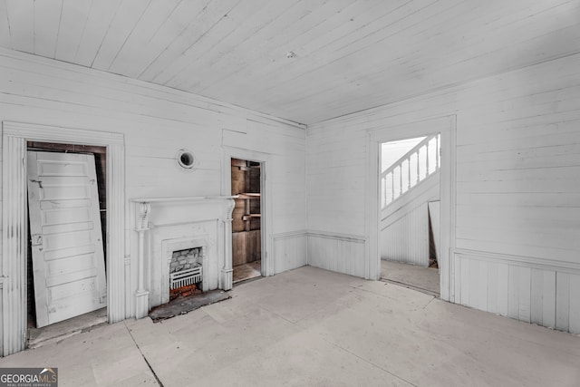 unfurnished living room featuring wooden walls