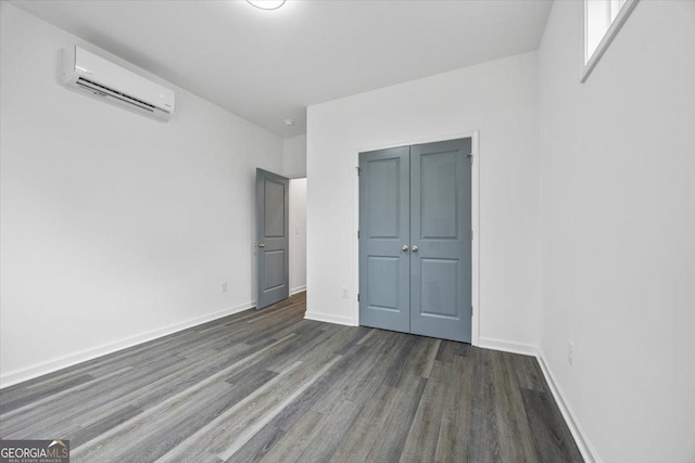 unfurnished bedroom with a wall unit AC, a closet, and dark hardwood / wood-style flooring