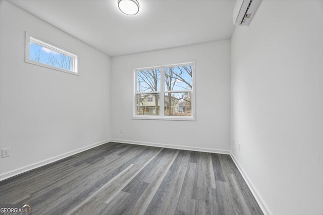 spare room featuring dark hardwood / wood-style flooring and a wall unit AC