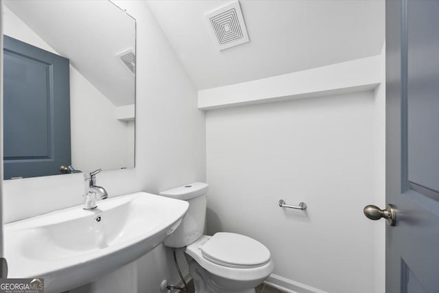 bathroom with toilet, vaulted ceiling, and sink