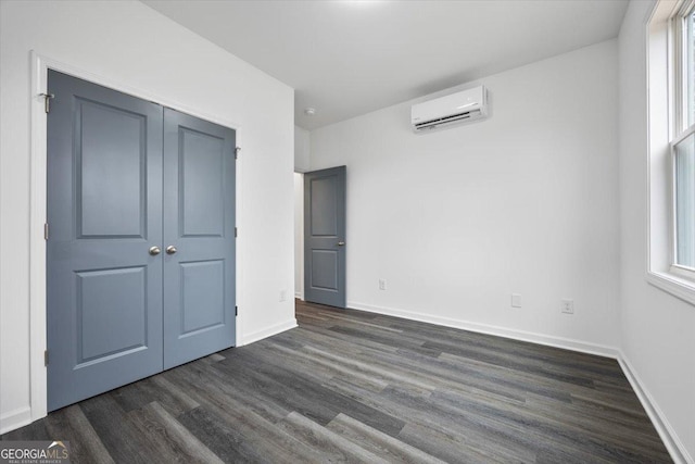 unfurnished bedroom featuring a closet, dark hardwood / wood-style floors, and a wall mounted air conditioner