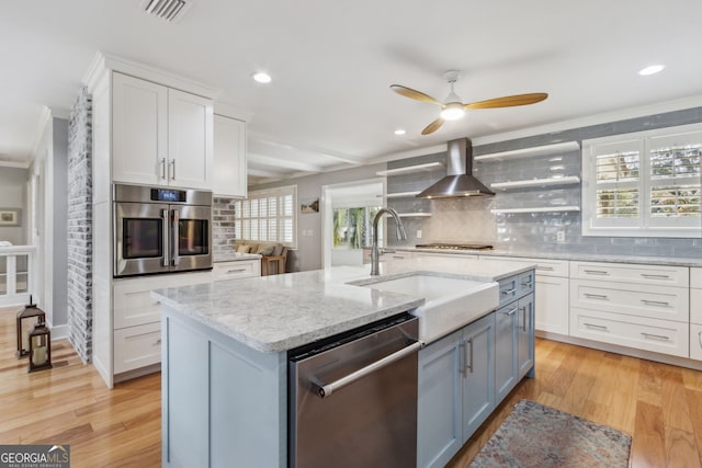 kitchen featuring an island with sink, white cabinetry, island exhaust hood, light hardwood / wood-style floors, and stainless steel appliances