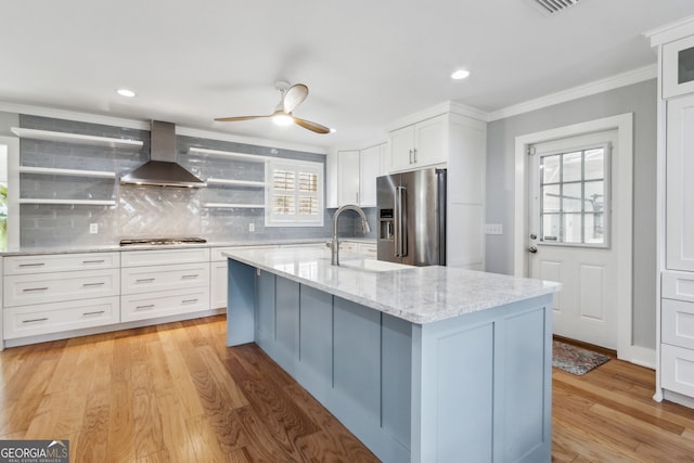 kitchen featuring white cabinetry, high quality fridge, island range hood, and a center island with sink