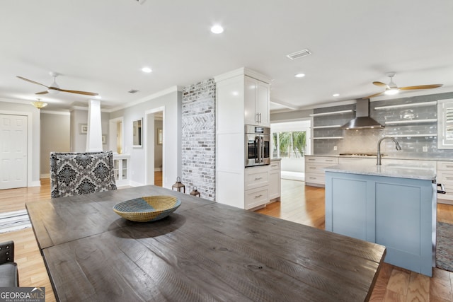 unfurnished dining area featuring crown molding, sink, ceiling fan, and light hardwood / wood-style flooring