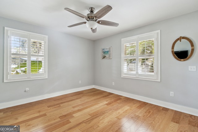 empty room featuring ceiling fan, light wood-type flooring, and a wealth of natural light