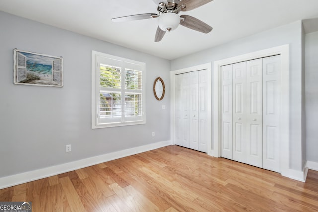 unfurnished bedroom featuring multiple closets, ceiling fan, and light wood-type flooring