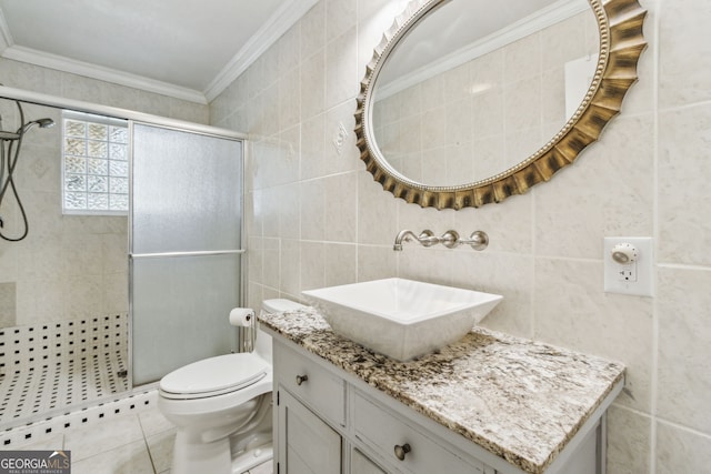 bathroom featuring tile walls, ornamental molding, vanity, toilet, and a shower with door