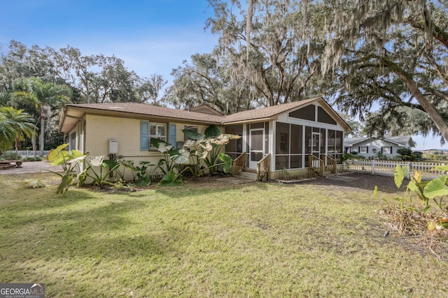 rear view of property with a yard and a sunroom