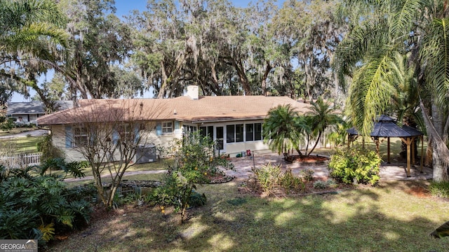 rear view of property featuring a gazebo and a lawn