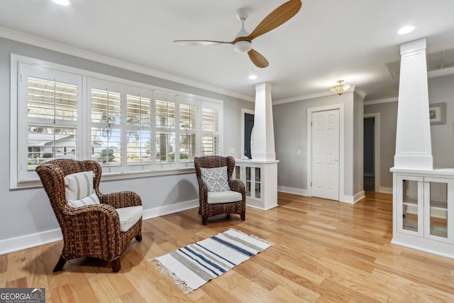 living area featuring ornate columns, ornamental molding, ceiling fan, and light wood-type flooring