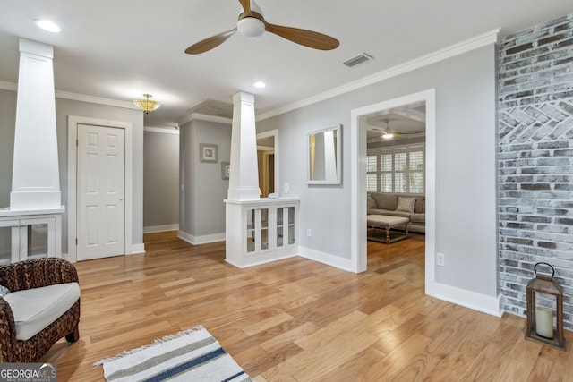 sitting room with crown molding, decorative columns, ceiling fan, and light wood-type flooring