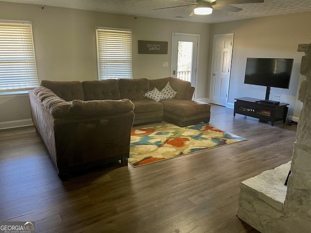 living room with dark wood-type flooring, ceiling fan, a healthy amount of sunlight, and a textured ceiling