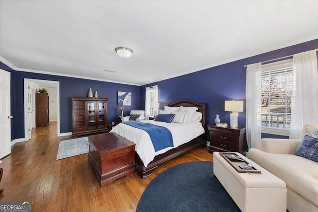 bedroom with ornamental molding and hardwood / wood-style floors