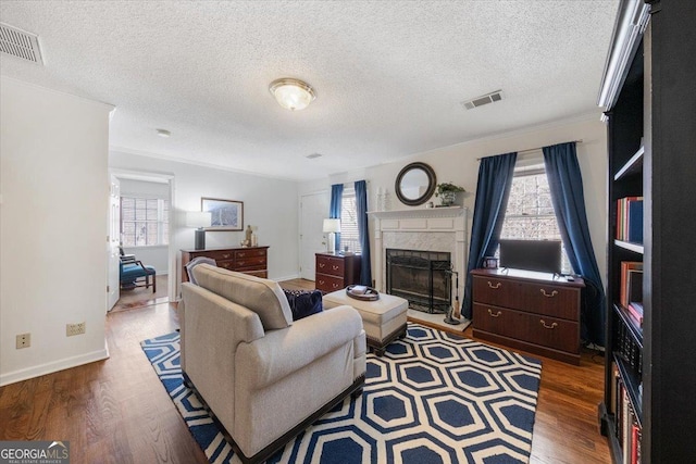 living room featuring a fireplace, dark wood-type flooring, a textured ceiling, and a healthy amount of sunlight