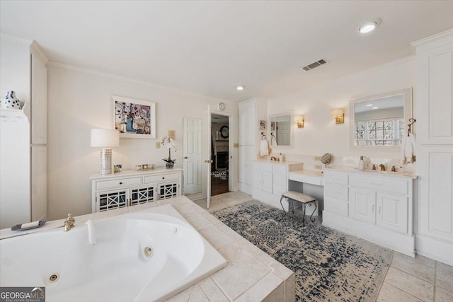 bathroom with tiled bath, ornamental molding, and vanity