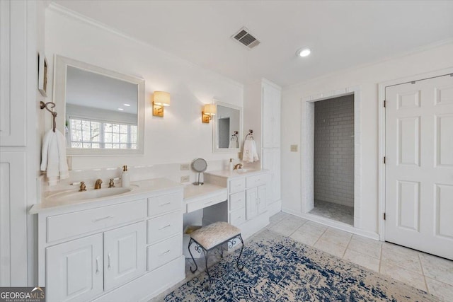 bathroom with vanity, tile patterned floors, crown molding, and tiled shower