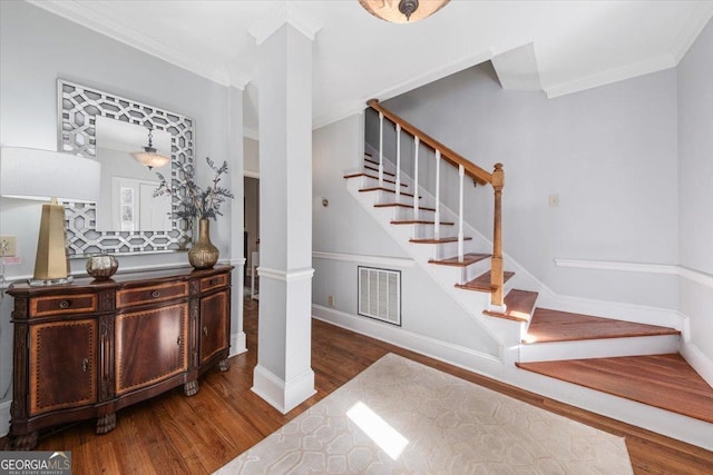 staircase with ornate columns, ornamental molding, and hardwood / wood-style flooring