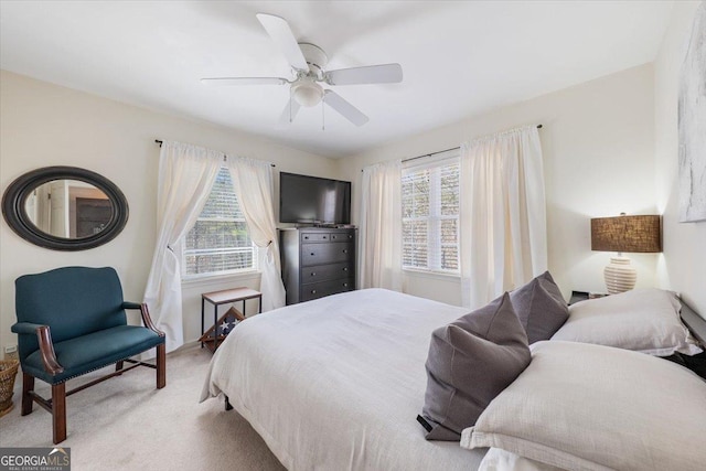 bedroom featuring light carpet, ceiling fan, and multiple windows