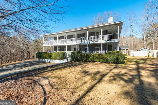 back of property featuring a balcony, a yard, and a porch