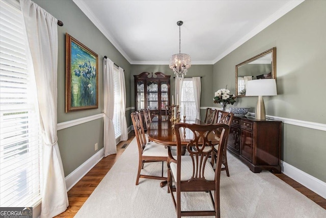 dining space with a notable chandelier, ornamental molding, and hardwood / wood-style flooring