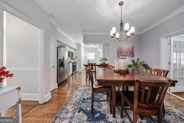 dining area featuring a chandelier, crown molding, and wood-type flooring