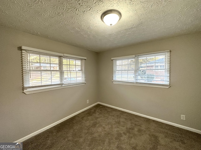 unfurnished room with a textured ceiling and dark colored carpet