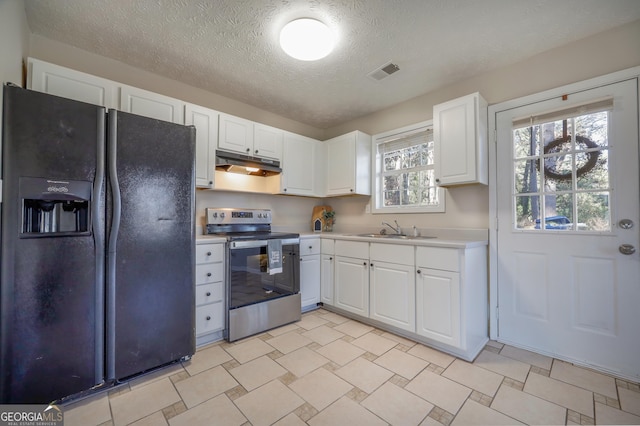 kitchen featuring sink, a textured ceiling, stainless steel electric range oven, white cabinets, and black fridge