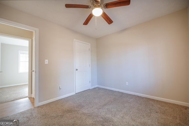 unfurnished bedroom featuring ceiling fan, light colored carpet, and connected bathroom