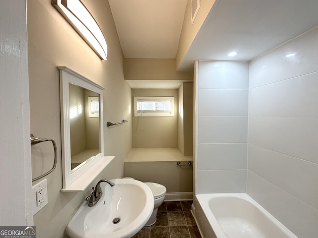 bathroom featuring toilet, a tub to relax in, and sink