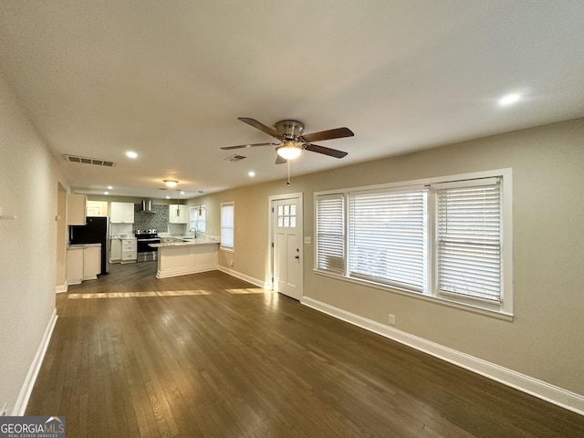 unfurnished living room featuring ceiling fan, sink, and dark wood-type flooring