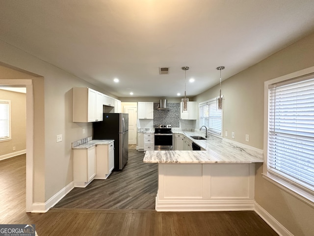 kitchen with white cabinetry, kitchen peninsula, appliances with stainless steel finishes, decorative light fixtures, and sink