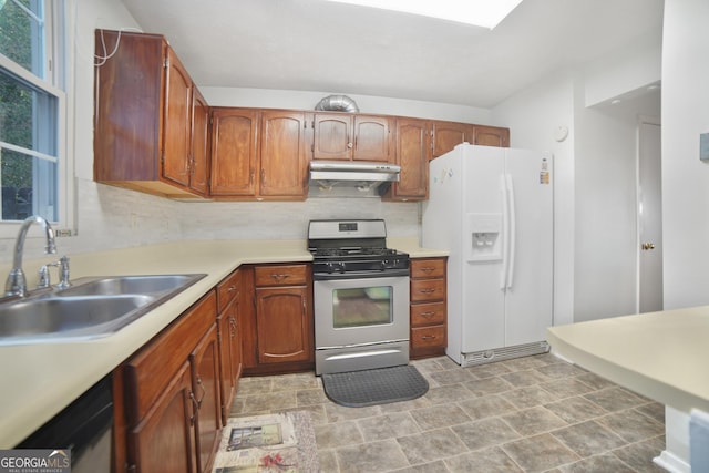 kitchen featuring white refrigerator with ice dispenser, sink, stainless steel range with gas stovetop, and decorative backsplash