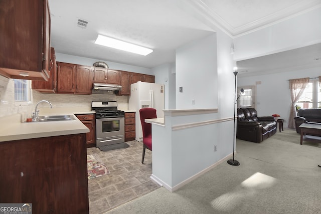 kitchen featuring tasteful backsplash, stainless steel gas stove, ornamental molding, white refrigerator with ice dispenser, and sink