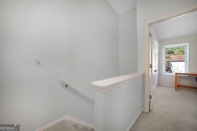 corridor featuring lofted ceiling and light colored carpet