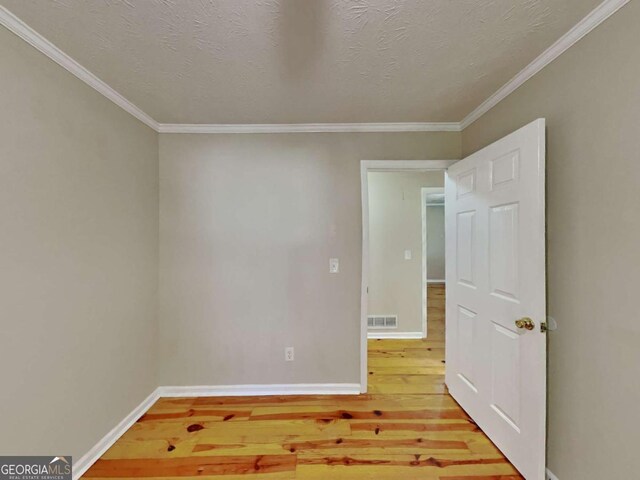 unfurnished room featuring hardwood / wood-style floors, crown molding, and a textured ceiling