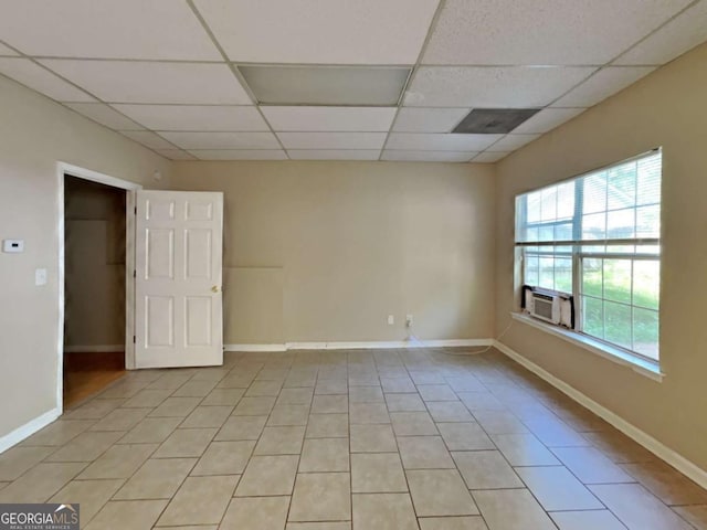 spare room featuring a paneled ceiling, light tile patterned flooring, and cooling unit