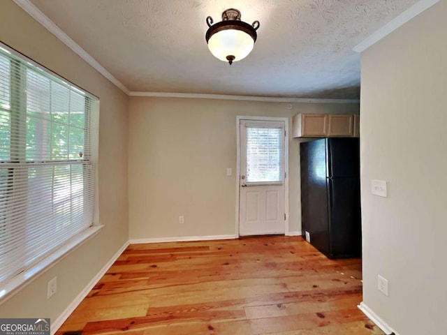 kitchen with light hardwood / wood-style floors, light brown cabinets, a textured ceiling, ornamental molding, and black refrigerator