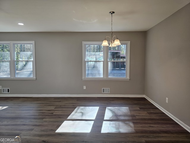 unfurnished dining area featuring an inviting chandelier and dark hardwood / wood-style flooring