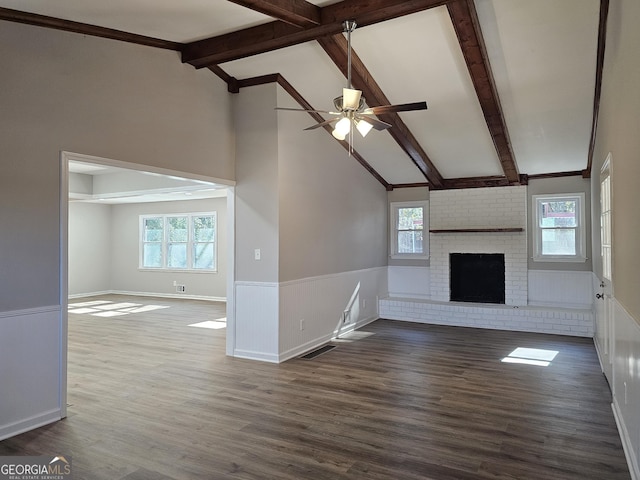 unfurnished living room with dark hardwood / wood-style floors, a brick fireplace, beam ceiling, and plenty of natural light