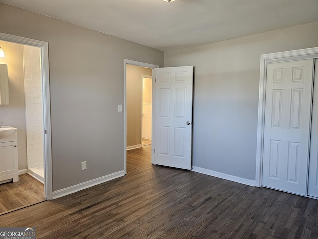 unfurnished bedroom with dark wood-type flooring, ensuite bathroom, and sink