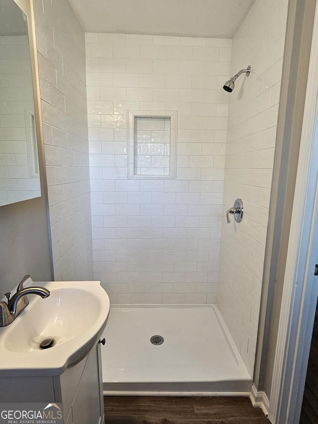 bathroom featuring a tile shower, wood-type flooring, and vanity