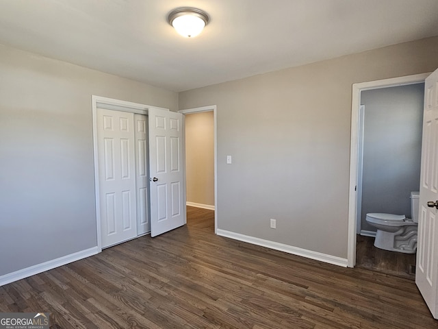 unfurnished bedroom with ensuite bath, a closet, and dark hardwood / wood-style floors