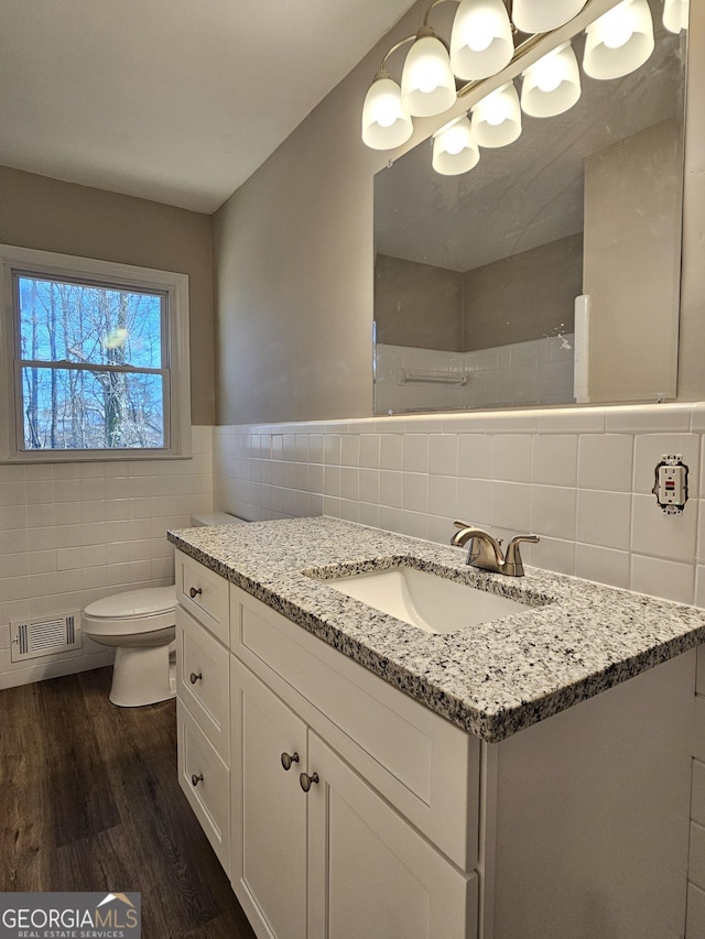 bathroom featuring toilet, tile walls, hardwood / wood-style floors, and vanity