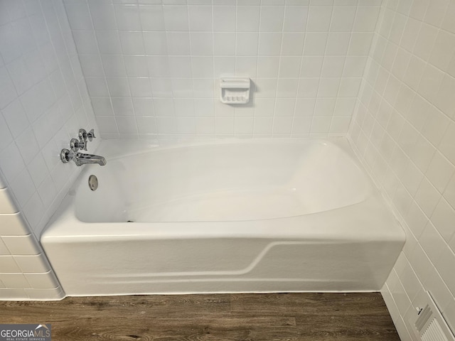 bathroom with hardwood / wood-style flooring and a washtub