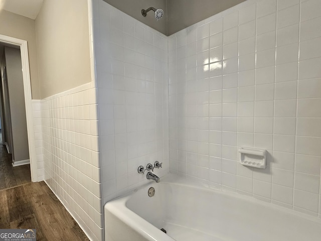 bathroom with tile walls, tub / shower combination, and wood-type flooring