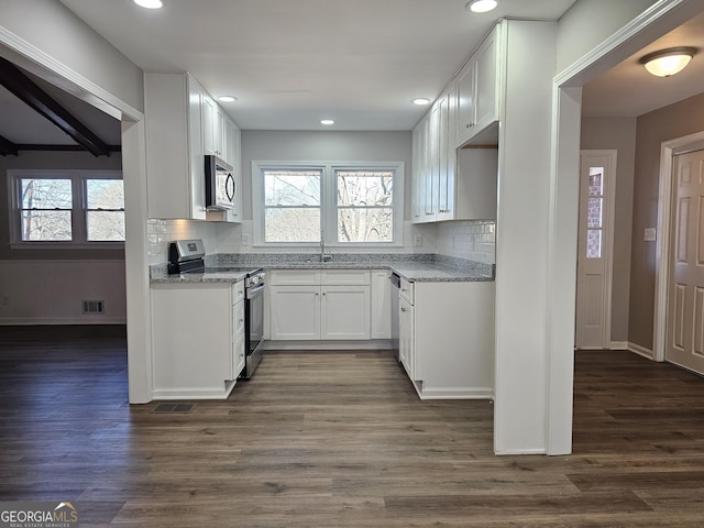 kitchen with dark hardwood / wood-style floors, appliances with stainless steel finishes, white cabinetry, and light stone countertops