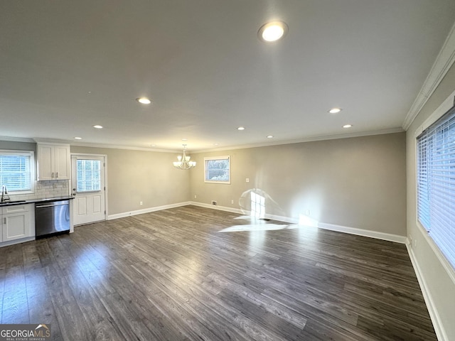 unfurnished living room featuring a chandelier, crown molding, dark hardwood / wood-style floors, and sink