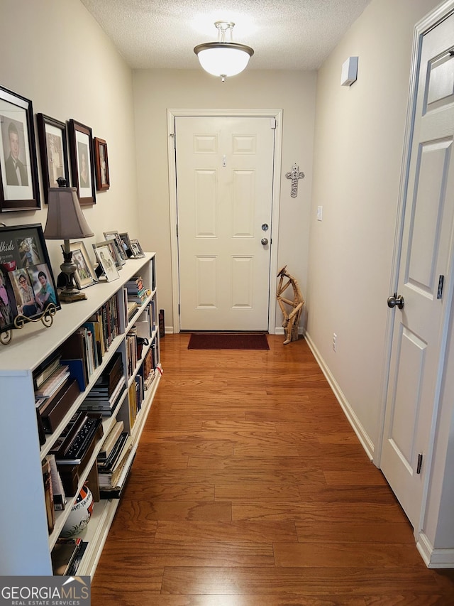 entryway with a textured ceiling and wood-type flooring